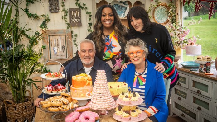 GBBO presenters sit around some delicious cakes.